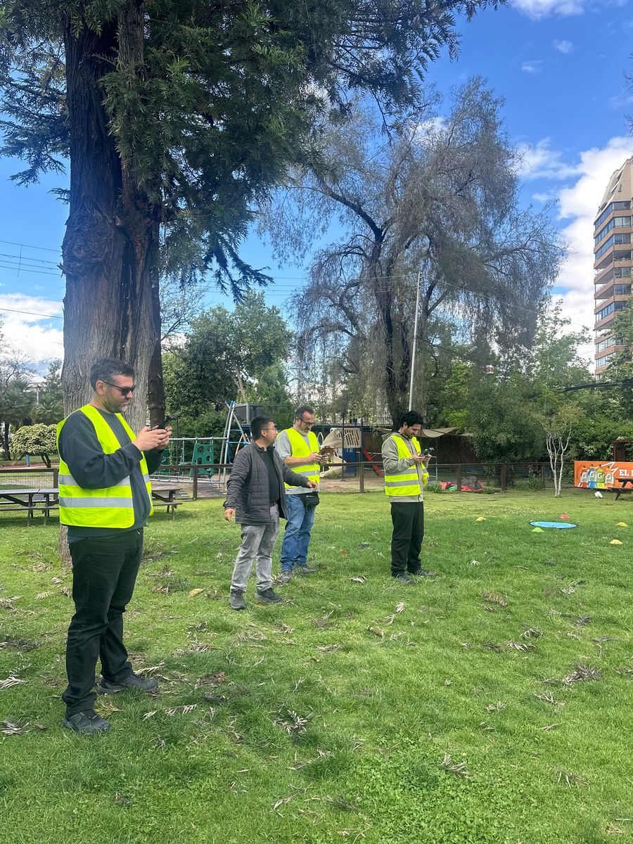 Funcionarios de la Municipalidad de Estación Central con chaleco reflectante y control en mano durante la práctica de vuelo, junto al instructor de AÉREO