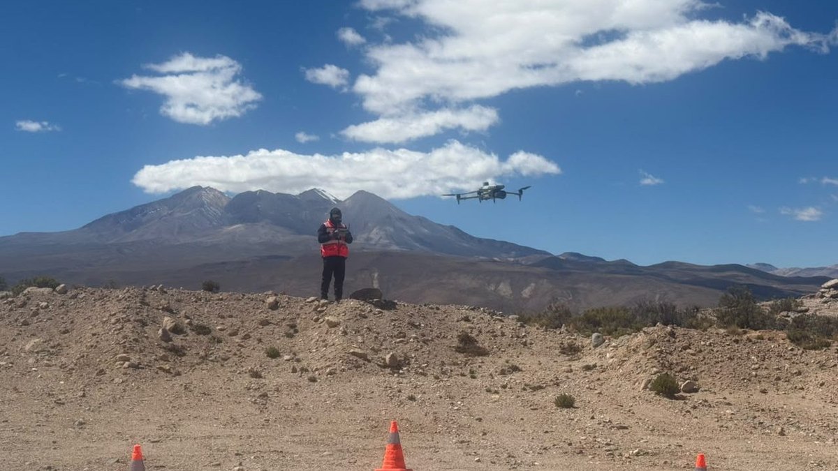 Operación de AÉREO en el altiplano: el dron en vuelo bajo un cielo despejado, con el piloto y los conos de la zona de despegue