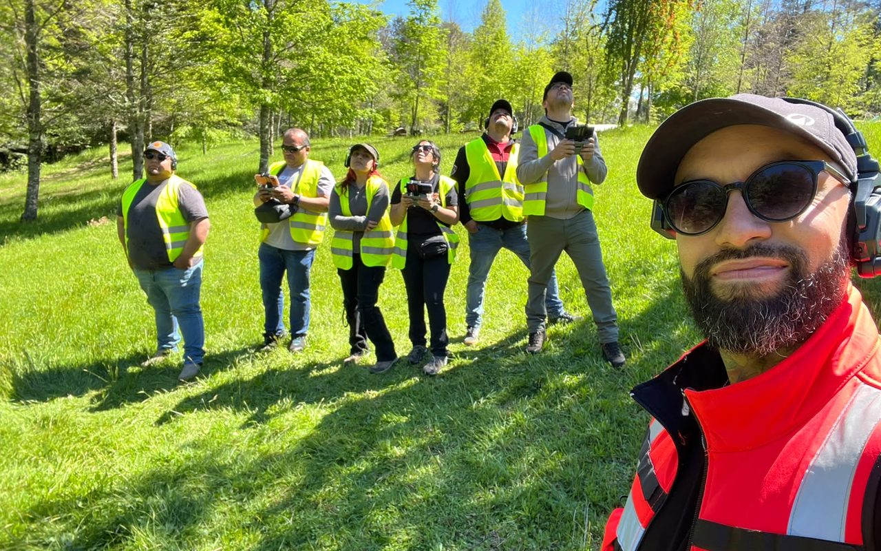 Voluntarios de Bomberos de Curacautín con chaleco reflectante y mando en la mano, siguiendo el dron con la vista durante la práctica