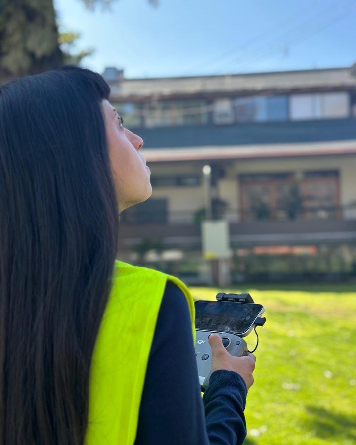 Alumna de AÉREO con el control DJI en la mano, siguiendo el dron con la vista