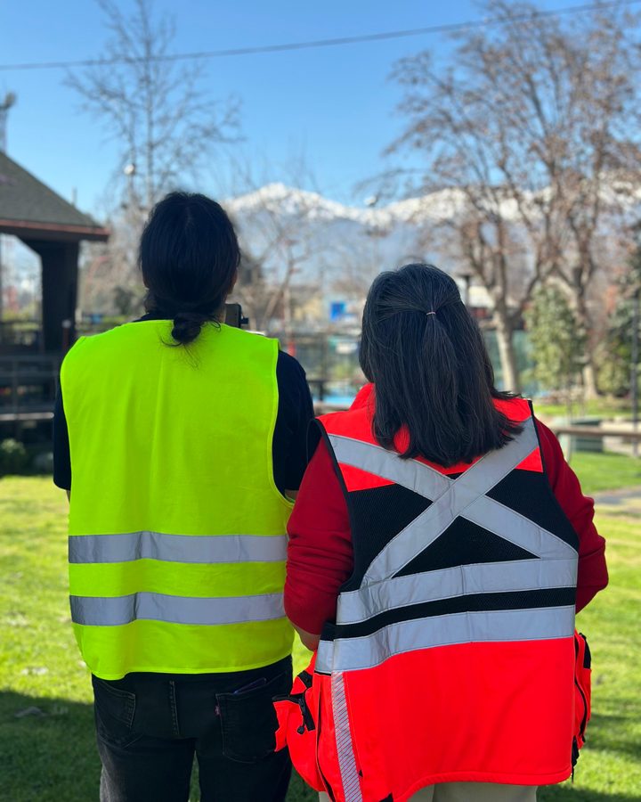 Dos alumnos de AÉREO con chalecos reflectantes observando el vuelo, con la cordillera nevada de fondo