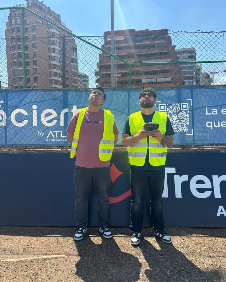 Dos alumnos siguiendo el dron en la cancha, en un día despejado