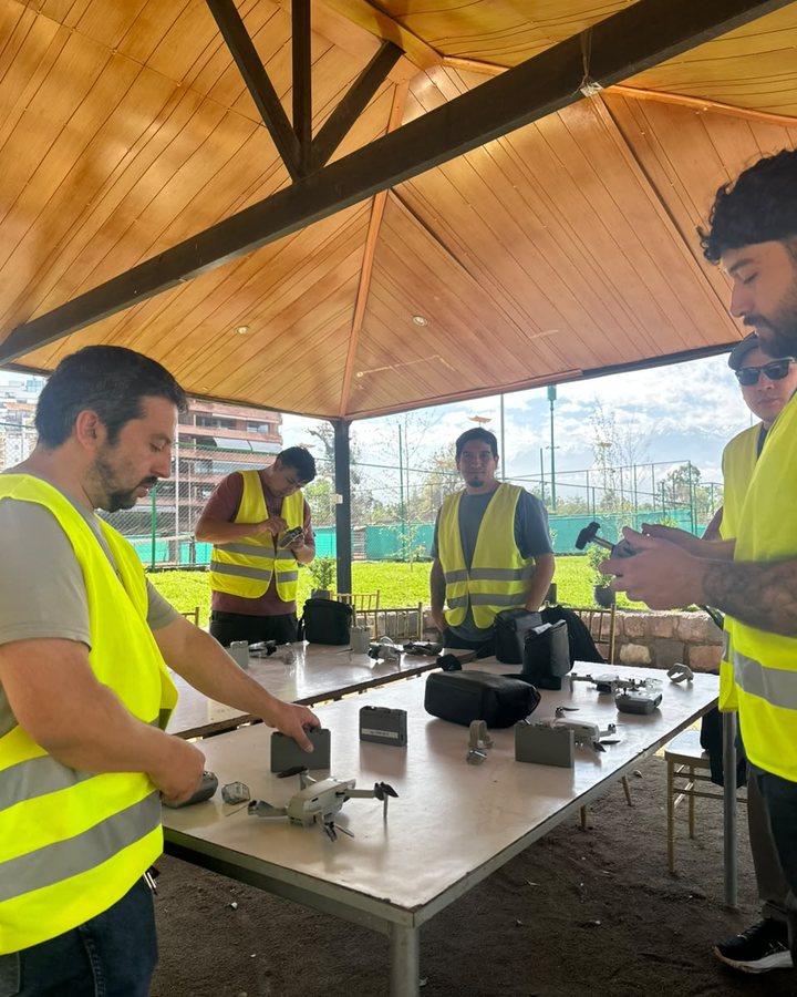 Alumnos armando los drones sobre la mesa del domo antes de salir a volar