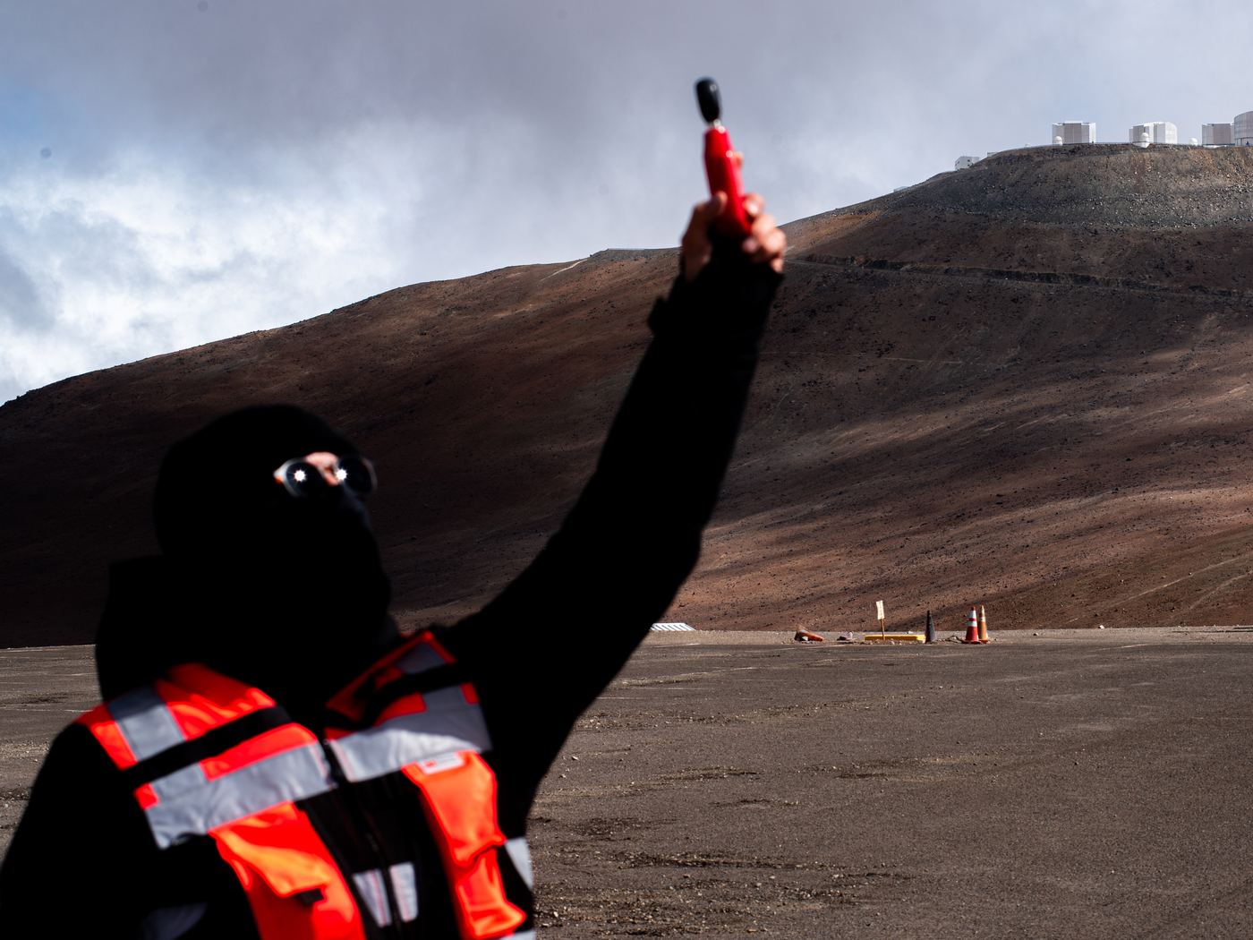 Instructor de AÉREO levantando el dron antes del despegue, con la cumbre de Paranal al fondo