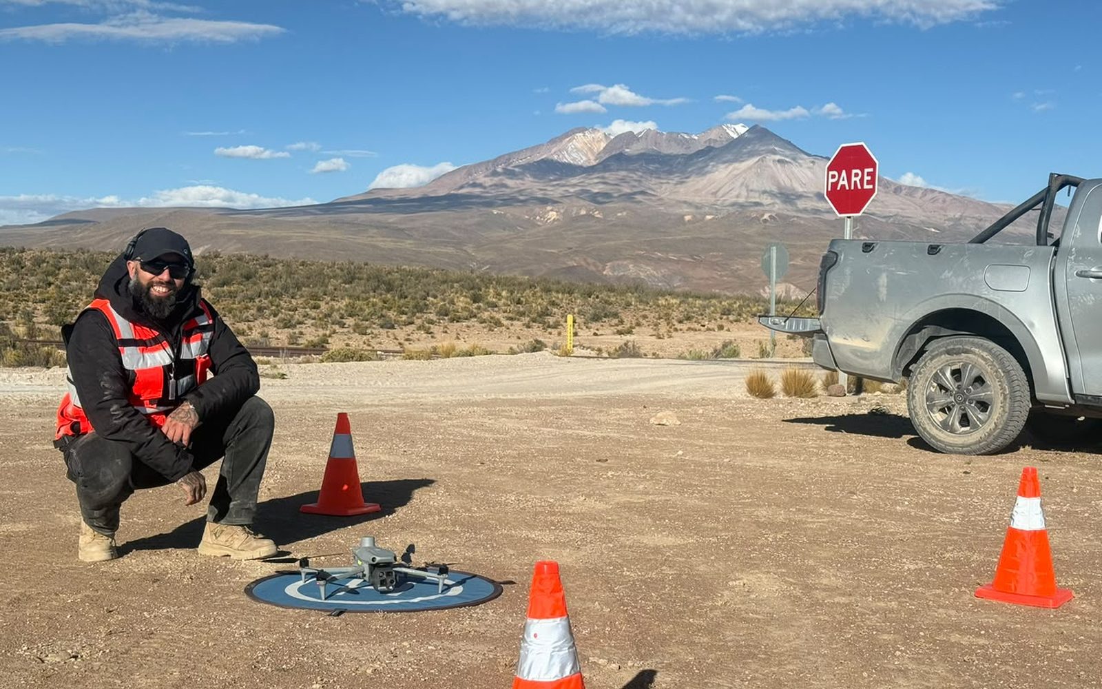 Piloto de AÉREO junto al dron sobre su plataforma de despegue, con conos de seguridad y el altiplano chileno detrás