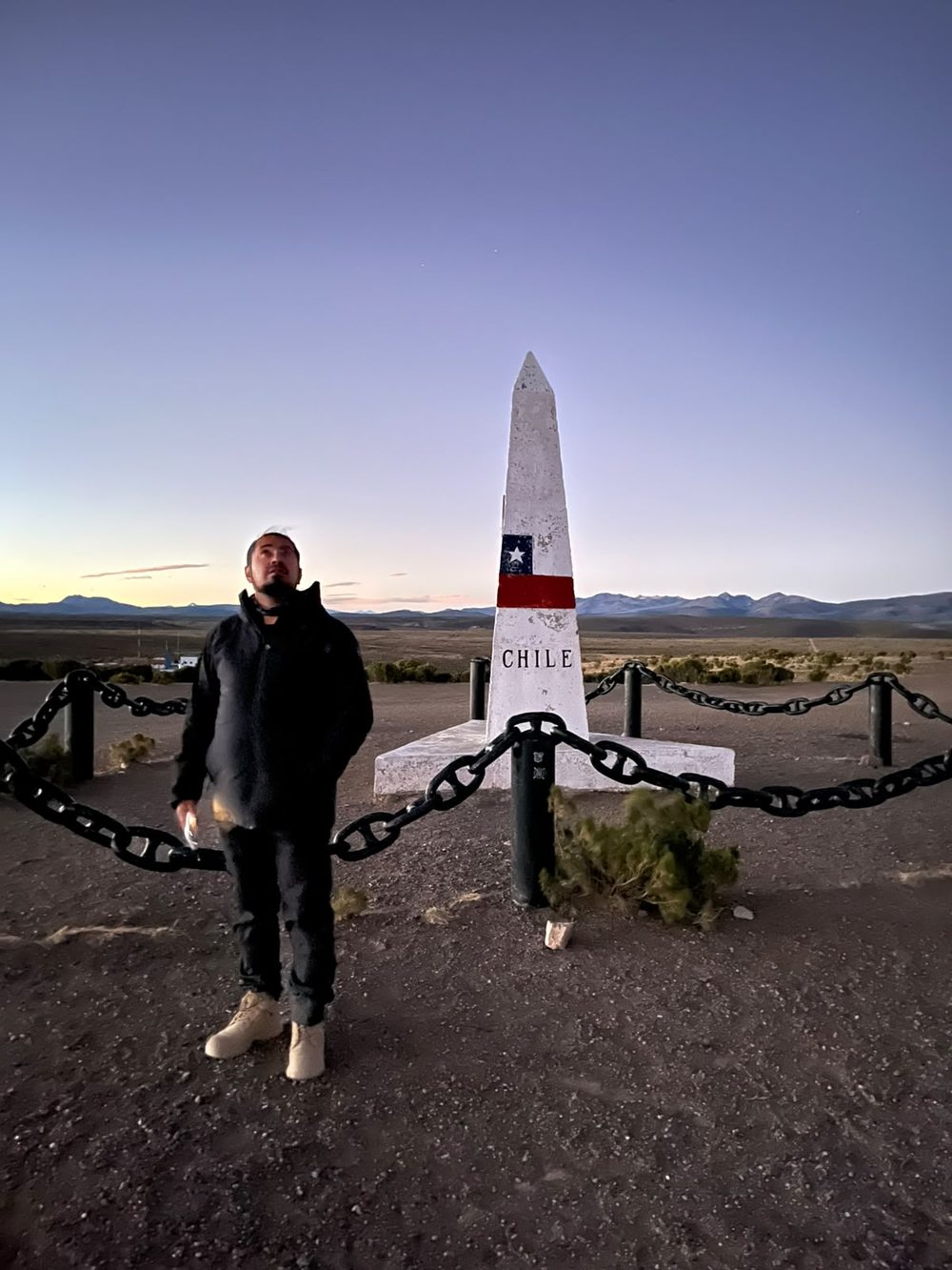 Hito fronterizo con la bandera de Chile en el altiplano, al atardecer