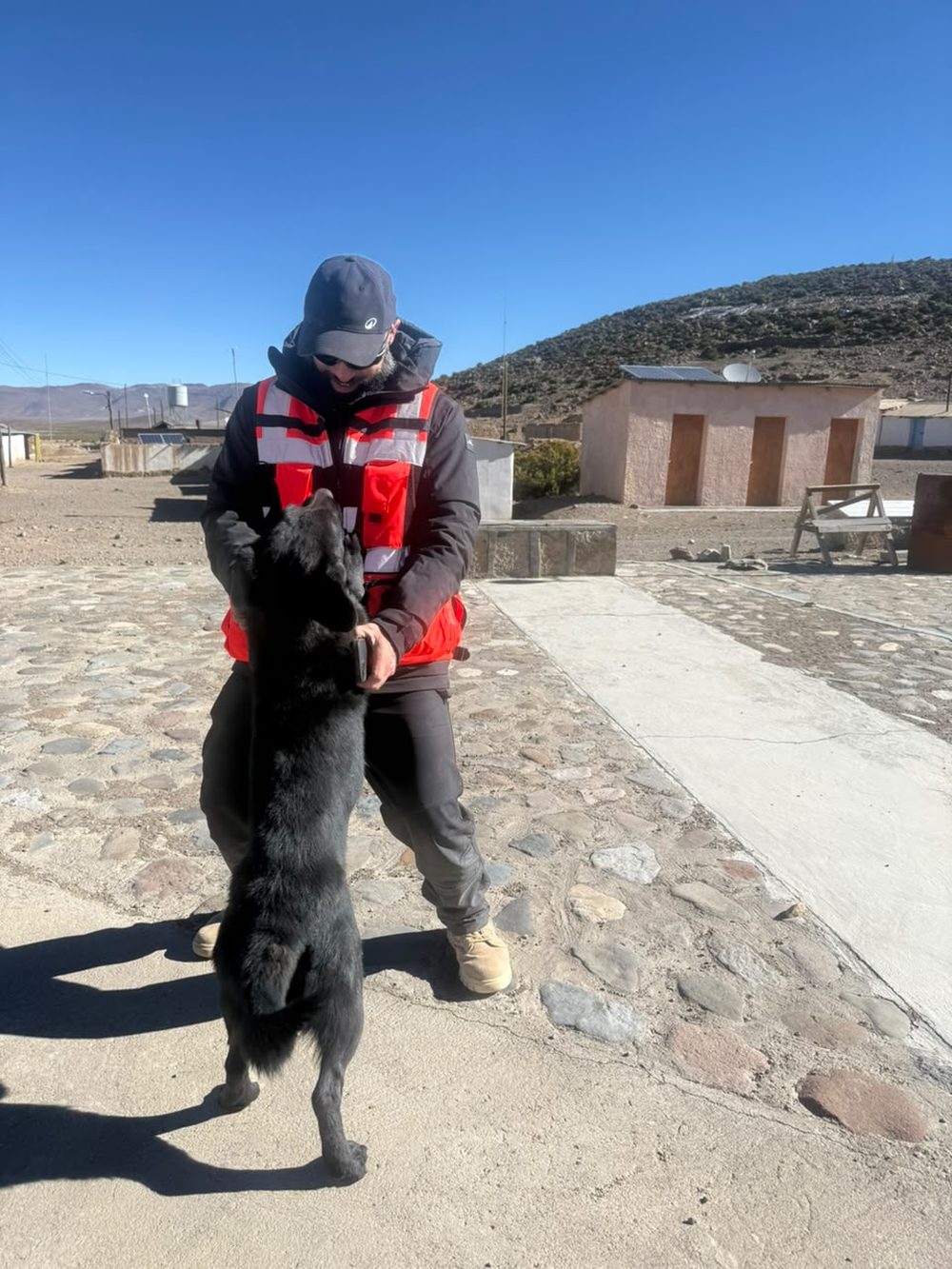 Calle del pueblo altiplánico, con un perro saludando a uno de los pilotos